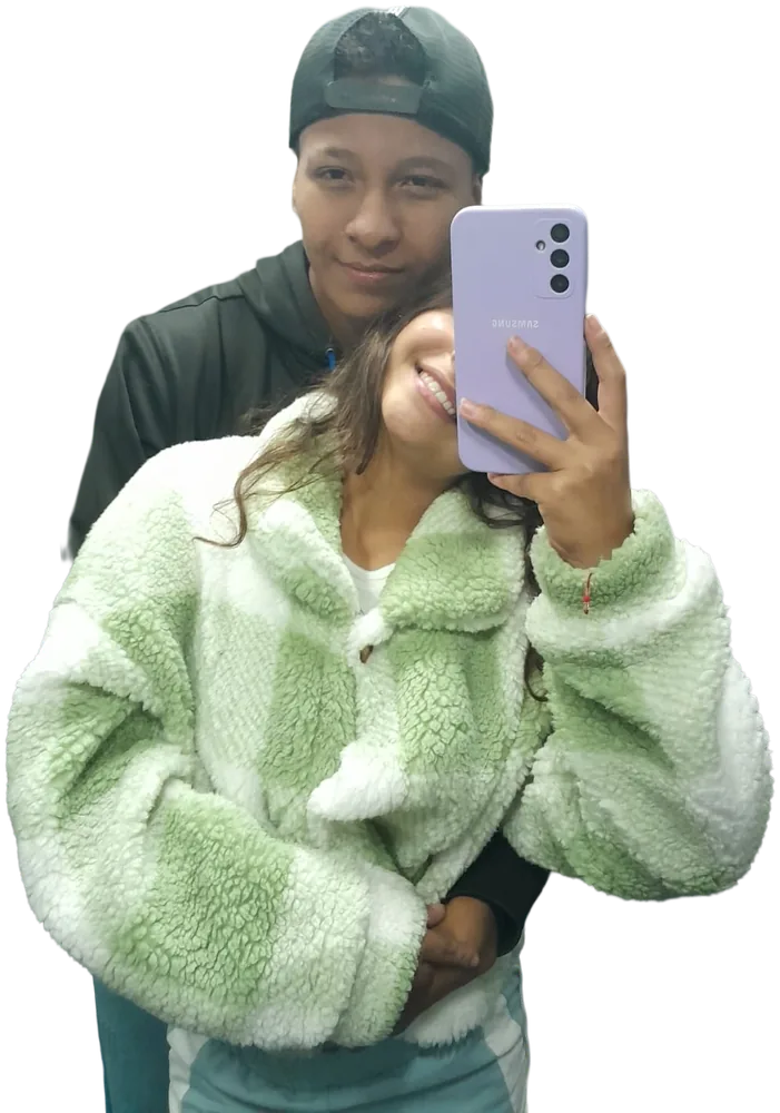 Ella sonríe con chaqueta verde y él la abraza por detrás
