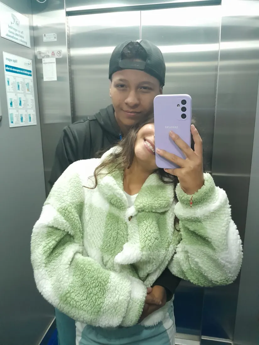 Ella sonríe con chaqueta verde y él la abraza